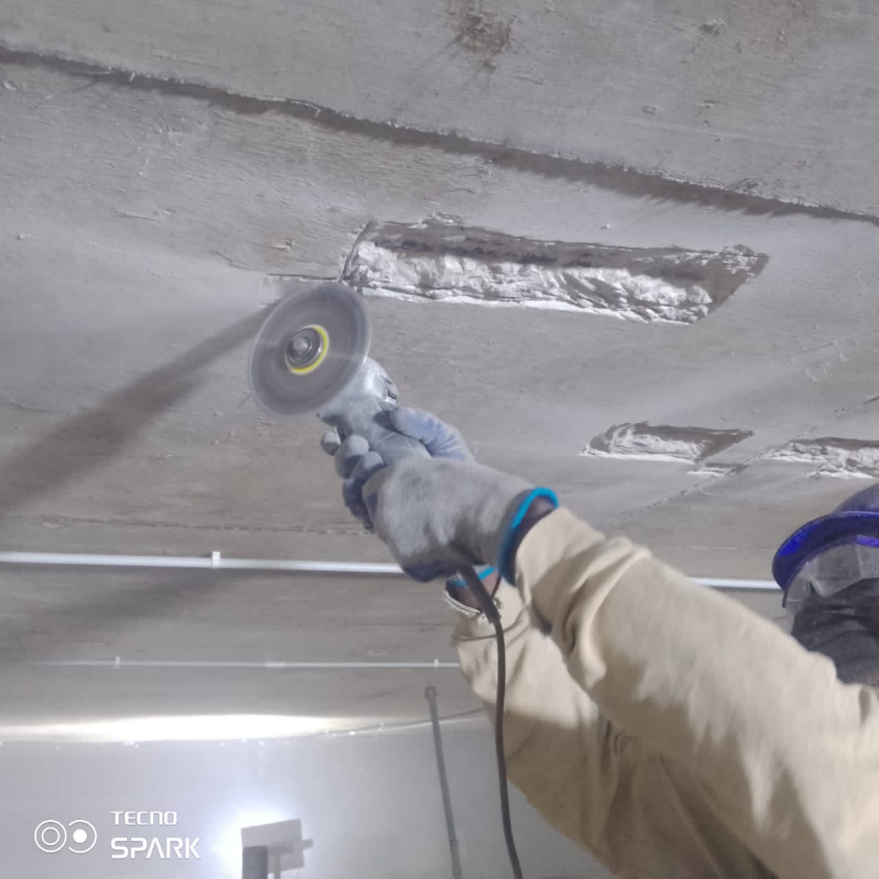 Grinding patch repairs on the basement soffit after mortar cure