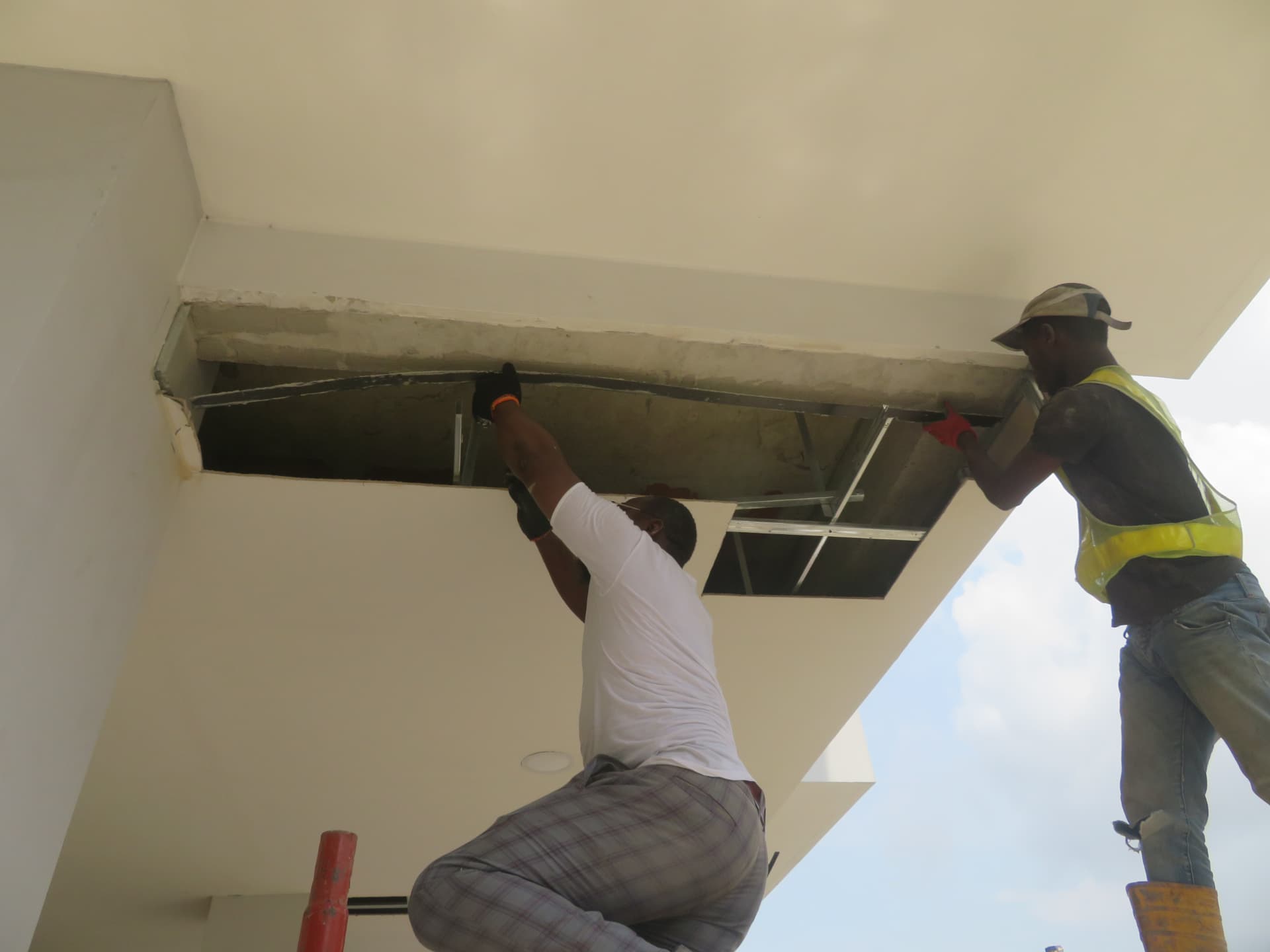 Two technicians bonding laminate to the exposed soffit beam