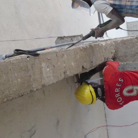 Operatives breaking out deteriorated concrete from a beam soffit