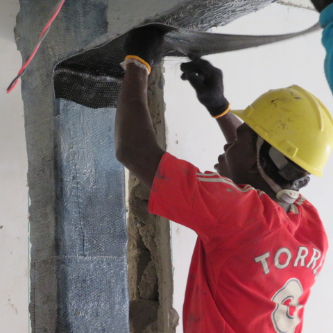 Technician bonding carbon fibre sheet to a beam soffit