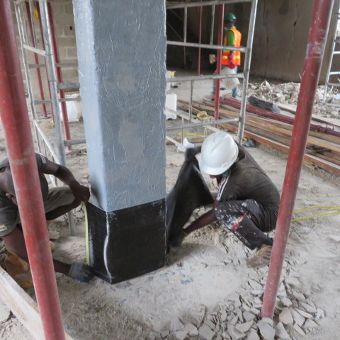 Crew wrapping carbon fibre fabric around the base of a primed column
