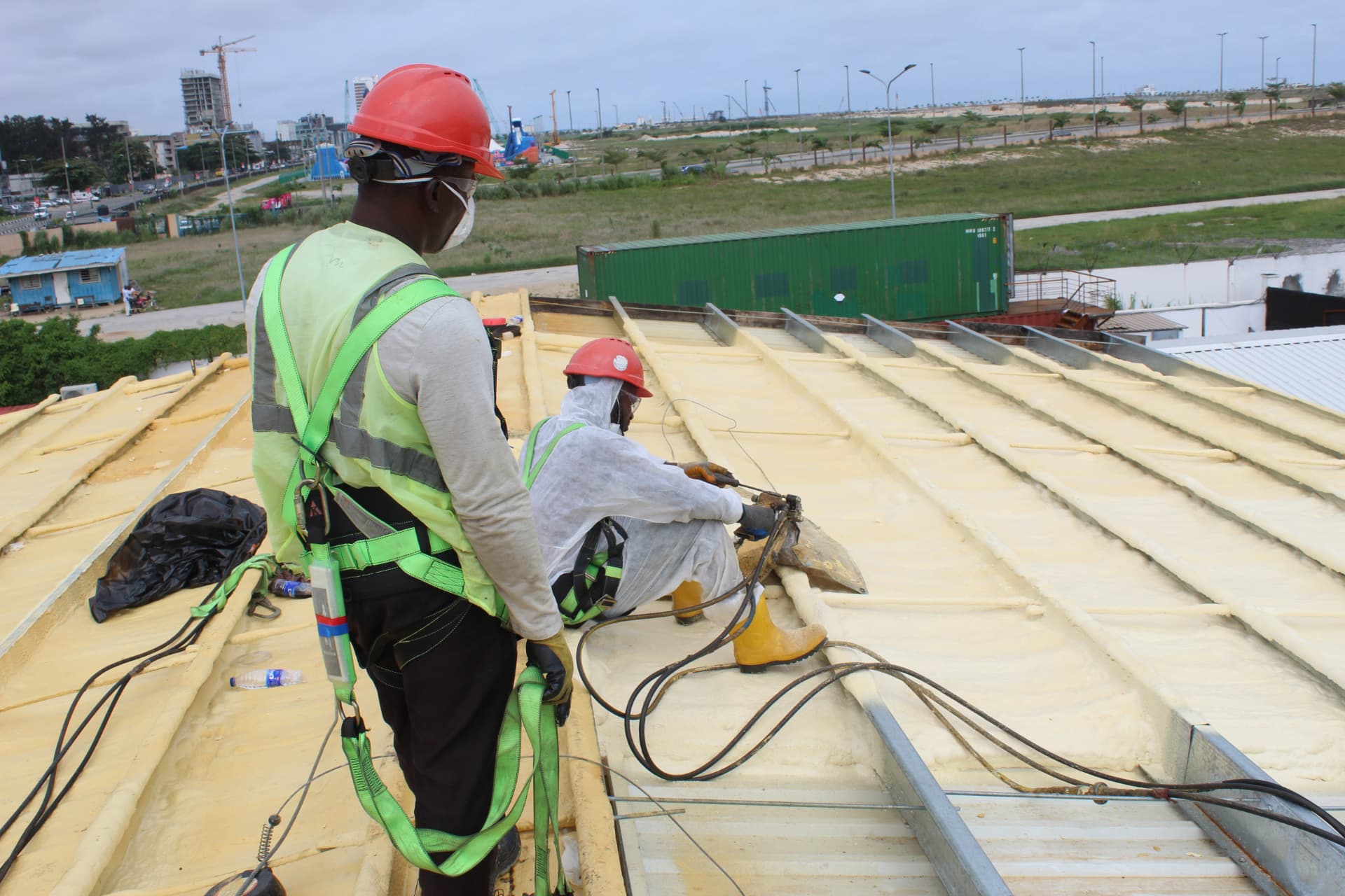 Operative in protective suit spraying foam while a colleague supervises